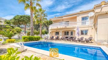 Der private Außenpool der Villa Estrella mit klarem blauem Wasser, Sonnenliegen und Palmen vor einem blauen Himmel.