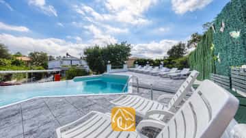 Privater Pool mit mehreren weißen Kunststoff-Sonnenliegen auf einer gefliesten Terrasse der Villa Geolouk in Spanien.