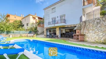 Privater Pool mit blauen Sonnenliegen und Steinterrasse in der Villa Nicky, die durch eine weiße mehrstöckige Außenfassade, einen Außengrill und einen offenen Terrassen-Essbereich besticht.