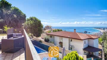 Balkon mit dunklen Polyrattan-Sesseln und Blick auf die Villa Mauri, die umliegenden Häuser und das blaue Meer.