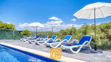 Weiße und blaue Sonnenliegen reihen sich am Pool der Villa Fransisca auf, begleitet von weißen Sonnenschirmen vor einem blauen Himmel.