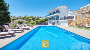 Rechteckiger Swimmingpool mit blauen Mosaikfliesen und mehreren Sonnenliegen auf der gepflasterten Terrasse der Villa SummerDream in Spanien.