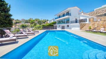 Rechteckiger Swimmingpool mit blauen Mosaikfliesen und mehreren Sonnenliegen auf der gepflasterten Terrasse der Villa SummerDream in Spanien.