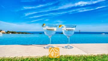 Zwei Gin-Cocktails mit Zitronengarnitur am Rand des Infinity-Pools der Villa Chanel, mit Blick auf das azurblaue Meer und den Himmel.