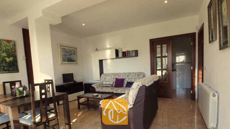 Wohn- und Essbereich der Villa Noa mit gemusterten Sofas, einem Esstisch aus Holz und Fliesenböden.