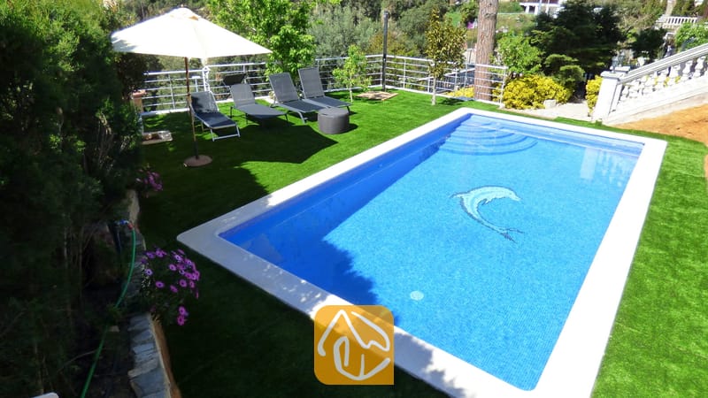 Privater Pool mit Delfinmosaik in der Villa Noa, umgeben von Kunstrasen, Sonnenliegen und einem Sonnenschirm.