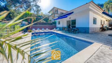 Privater Pool und Terrasse in der Villa Zarita mit blau gefliestem Wasser, weißen Sonnenliegen und einem Essbereich im Freien unter einer blauen Markise.
