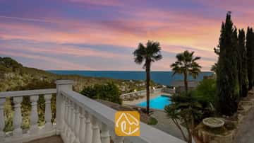 Terrasse mit Blick auf die Villa Tropicana, privatem Swimmingpool, Palmen und Meerblick unter einem rosa- und blauen Abendhimmel.