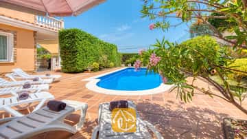 Das private Außenbad der Villa Primavera ist von einer gefliesten Terrasse, weißen Sonnenliegen mit gerollten dunklen Handtüchern und blühenden rosafarbenen Oleanderzweigen umgeben.