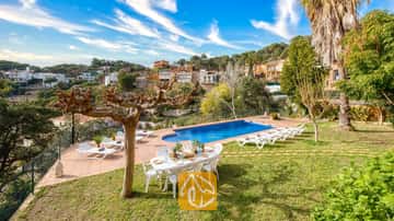 Privater Pool in der Villa Marysol, umgeben von einer gefliesten Terrasse, einer Rasenfläche, einem Esstisch mit Stühlen und Sonnenliegen vor einer malerischen Hangkulisse
