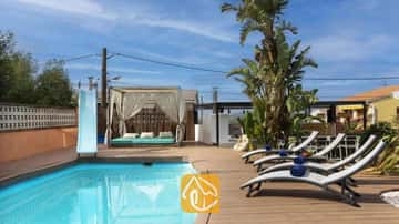 Privater Pool mit blauer Rutsche, Holzterrasse, grauen Sonnenliegen mit blauen Handtüchern und einer Vorhang-Cabana in der Villa Soleia.